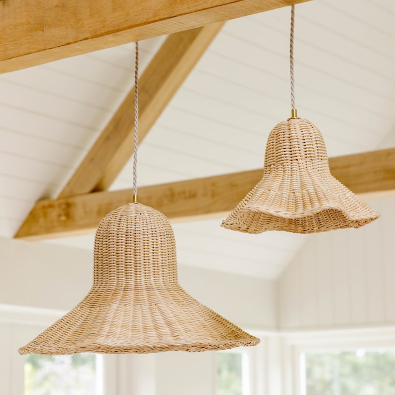 K&ouml;nnte beinhalten: Zwei geflochtene H&auml;ngeleuchten aus Weide h&auml;ngen an einem Holzbalken. Die Leuchten sind beige und haben eine Glockenform mit einem breiten, ausgestellten Boden.