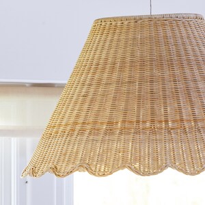 May include: A woven wicker lampshade with a scalloped edge. The shade is light brown and has a natural, rustic look.