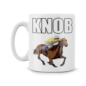 Könnte beinhalten: Weiße Keramiktasse mit schwarzem Umriss des Wortes "KNOB" und einem Cartoon-Bild eines braunen Pferdes mit einem Jockey in gelber und violetter Uniform.