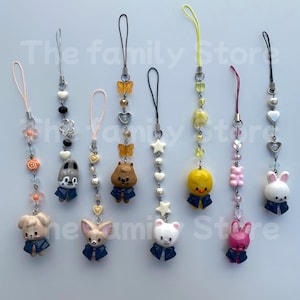 Peut inclure: Collection de breloques de téléphone colorées avec des figurines d'animaux, dont un chien, un lapin, un ours, un hamster, un canard et un chat. Chaque breloque porte une veste bleue et est ornée de perles, de cœurs, d'étoiles et de papillons. Les breloques mesurent environ 5 cm de long.