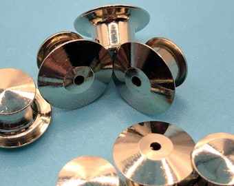 Op de afbeelding: Een close-up van tien zilveren metalen pin-achterkanten. De pin-achterkanten zijn rond en hebben een klein gaatje in het midden. Ze worden gebruikt om pinnen, badges en andere items aan kleding of stof te bevestigen.
