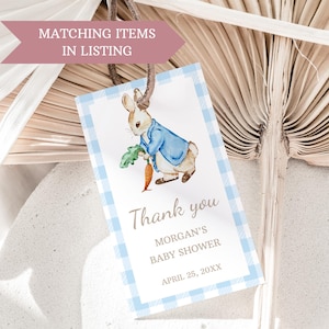 May include: A blue and white gingham thank you tag with a watercolor illustration of a bunny holding a carrot. The text reads "Thank you Morgan's Baby Shower April 25, 20XX".