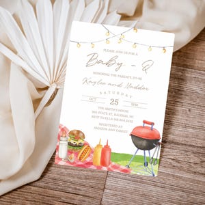 May include: Baby-Q baby shower invitation with watercolor illustrations of a hamburger, hot dog, condiments, and a red grill. The invitation includes the text "Baby-Q" and details for Kaylee and Maddox's baby shower.