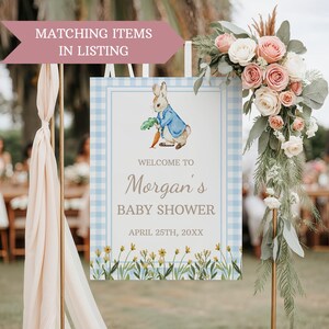 May include: A blue and white gingham welcome sign with a Peter Rabbit illustration. The sign says "Welcome to Morgan's Baby Shower, April 25th, 20XX".