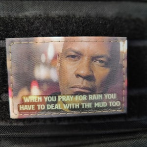 Könnte beinhalten: Ein braunes Patch mit einem Bild eines Männergesichts und dem Text "When you pray for rain you have to deal with the mud too."