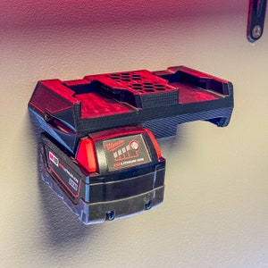 May include: A black and red Milwaukee M18 3.5 Ah REDLITHIUM-ION battery is mounted on a black plastic wall mount.