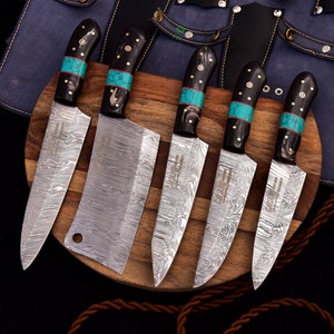 May include: Set of five kitchen knives with black handles and turquoise accents. The knives have a Damascus steel blade pattern and are displayed on a wooden cutting board.
