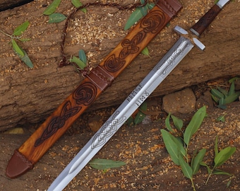May include: A silver sword with a wooden scabbard decorated with intricate carvings. The sword has a leather grip and a silver blade with a runic inscription that reads "VERFIST: HIMR".