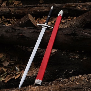 May include: A silver sword with a black handle and a red scabbard. The sword and scabbard are lying on a pile of brown logs.