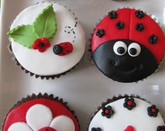 May include: Six cupcakes decorated with ladybug and flower themes. The cupcakes are frosted in white with red and black accents. One cupcake has a number "1" on it.