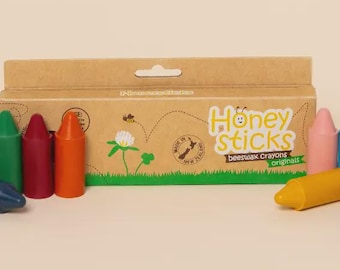 May include: A box of Honey Sticks beeswax crayons with a green, red, and orange crayon in front. The box is brown with green grass and a bee illustration. The text "Honey Sticks beeswax Crayons originals" is visible.
