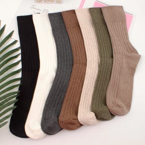 May include: Six pairs of ribbed socks in various colors, including black, white, gray, brown, beige, and green. The socks are folded and arranged in a row.