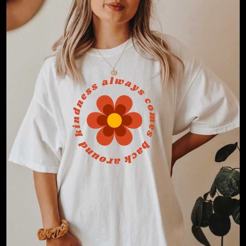 May include: White t-shirt with a red flower graphic and the text "kindness always comes back around".