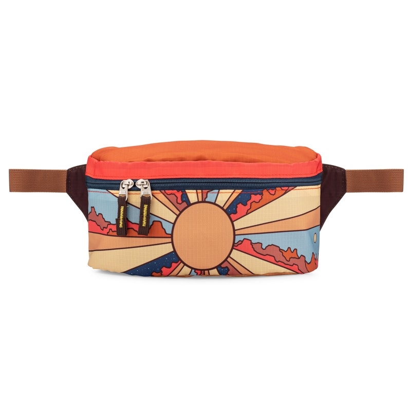 Front of fanny pack. Design features Grand Canyon National Park mountains, desert landscape, and sun with sunbeams. Primary colors are red, yellow, brown and blue.