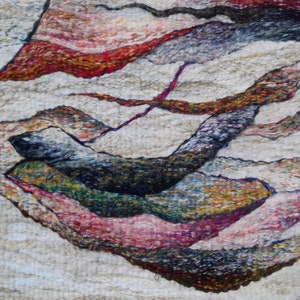 May include: Abstract wall art made of wool felt with a textured surface. The artwork features a variety of colors, including white, red, brown, green, and blue. The colors are arranged in a layered, abstract pattern.