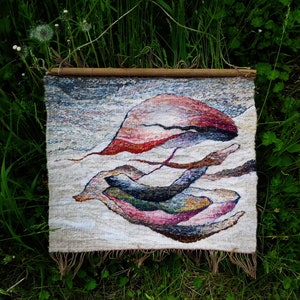 May include: A woven wall hanging with a beige background and abstract shapes in shades of red, pink, purple, blue, and green.