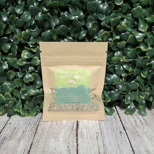 May include: A small, rectangular, light brown paper pouch with a clear window containing a dry, granular mixture. The label on the front is light green and features the text Green Dragon Roll and CrabCuisineCo.