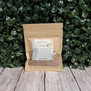 May include: A small, rectangular, light brown paper pouch containing a granular brown substance. The label reads Bugs in the Garden, followed by a list of ingredients including superworms, black soldier fly larvae, crickets, and CrabCuisineCo.
