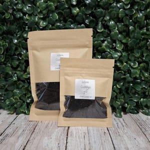 May include: Two light brown kraft paper stand-up pouches with clear windows containing dark brown granular worm castings. Each pouch features a white rectangular label with the text Worm Castings and a small snake icon above CrabCuisineCo.