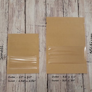 K&ouml;nnte beinhalten: Zwei rechteckige Beutel aus braunem Kraftpapier mit Sichtfenstern aus Kunststoff. Der kleine Beutel hat Au&szlig;enma&szlig;e von 6,86 cm x 8,89 cm und Innenma&szlig;e von 5,99 cm x 5,99 cm. Der mittlere Beutel hat Au&szlig;enma&szlig;e von 8,89 cm x 12,95 cm und Innenma&szlig;e von 7,87 cm x 9,91 cm.
