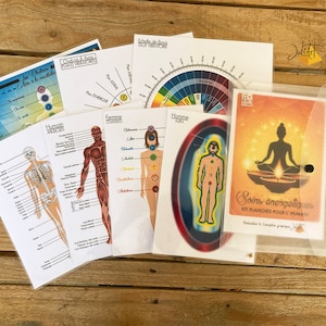 Könnte beinhalten: Ein Satz farbenfroher Diagramme und Schaubilder für energetisches Heilen, mit Illustrationen des menschlichen Körpers, der Chakren und der Aura. Die Diagramme sind auf weißem Papier gedruckt und befinden sich in einem durchsichtigen Plastikordner. Der Ordner trägt ein Etikett mit der Aufschrift "Soins énergétiques Kit planches pour l'humain".