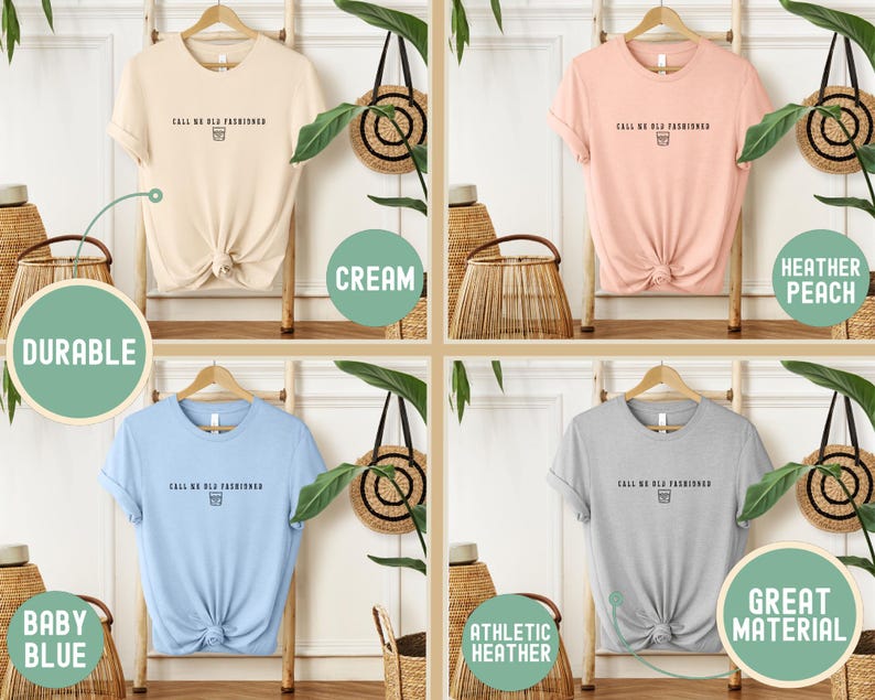 May include: Four t-shirts in cream, heather peach, baby blue, and athletic heather gray, each with the text "CALL ME OLD FASHIONED" and a small graphic. The shirts are displayed on wooden hangers.