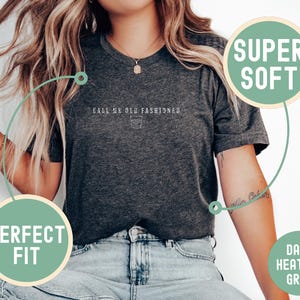 May include: Dark heather grey t-shirt with the text "Call Me Old Fashioned" and a small graphic of a cocktail glass. The shirt is described as "Super Soft" and a "Perfect Fit".