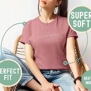 May include: Heather mauve t-shirt with the text "CALL ME OLD FASHIONED" in a light color. The shirt is a crew neck and is being worn with blue jeans. The shirt is labeled as "SUPER SOFT" and "PERFECT FIT".
