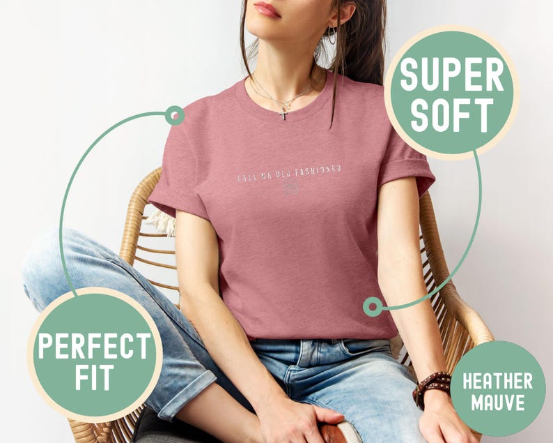 May include: Heather mauve t-shirt with the text "CALL ME OLD FASHIONED" in a light color. The shirt is a crew neck and is being worn with blue jeans. The shirt is labeled as "SUPER SOFT" and "PERFECT FIT".