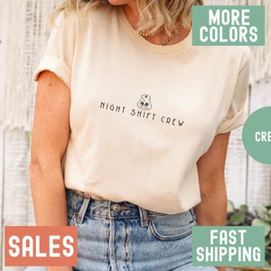 Peut inclure: Un t-shirt crème avec un dessin de dessin animé d'une infirmière avec le texte "Night Shift Crew".