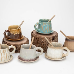 May include: Six ceramic mugs with wooden stirrers, each mug has a unique glaze and pattern. The mugs are arranged on wooden slices.