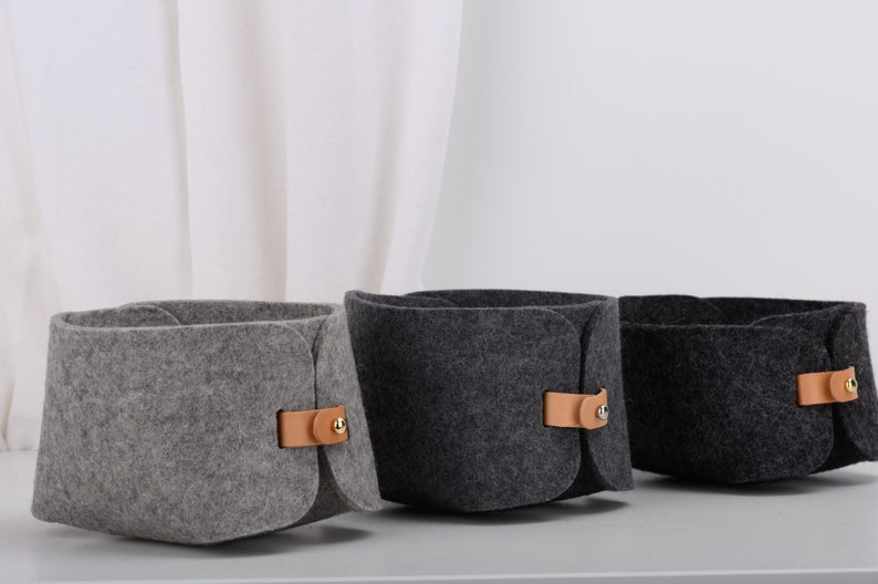 May include: Three felt storage baskets with leather handles. The baskets are gray, dark gray, and black.