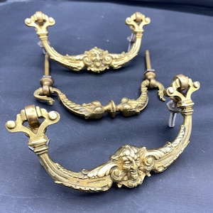 Set mit drei Schubladengriffen aus Bronze. Zwei zeigen die Gesichter grüner Männchen und stammen aus dem frühen 19. Jahrhundert.