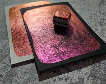 Puede incluir: Dos muestras de pintura metálica, una cobre y otra rosa, con un pequeño recipiente cuadrado de pintura metálica rosa etiquetado como "Andrew's".