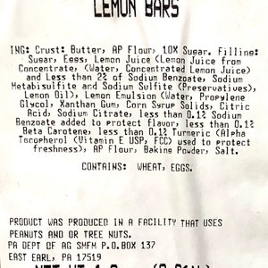 Peut inclure: Une &eacute;tiquette blanche avec du texte noir listant les ingr&eacute;dients des barres au citron. L'&eacute;tiquette indique "Lemon Bars" en haut et "NET WT 1.0 oz (0.0616)" en bas. Les ingr&eacute;dients comprennent du beurre, de la farine, du sucre, des &oelig;ufs, du jus de citron et des conservateurs.