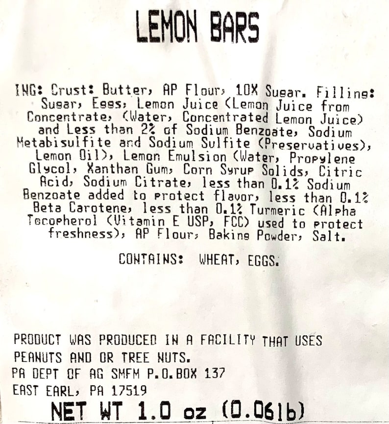 Peut inclure: Une &eacute;tiquette blanche avec du texte noir listant les ingr&eacute;dients des barres au citron. L'&eacute;tiquette indique "Lemon Bars" en haut et "NET WT 1.0 oz (0.0616)" en bas. Les ingr&eacute;dients comprennent du beurre, de la farine, du sucre, des &oelig;ufs, du jus de citron et des conservateurs.