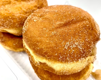 May include: A stack of four golden brown donuts with a cinnamon sugar coating.