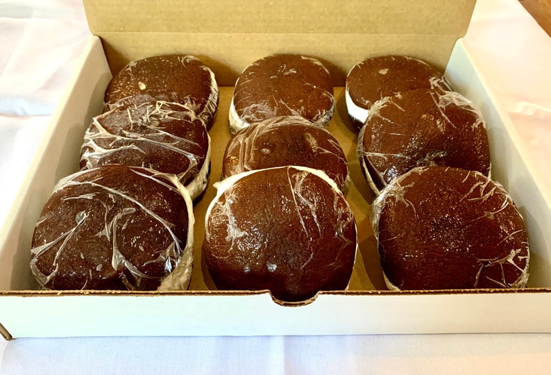May include: A box of nine chocolate-covered marshmallow treats, individually wrapped in clear plastic. The treats are arranged in three rows of three, with the tops of the treats facing the viewer.