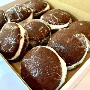 May include: A box of chocolate-covered marshmallow treats, individually wrapped in plastic. The treats are arranged in a single layer, with the chocolate side facing up.
