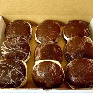 May include: A box of nine chocolate-covered marshmallow treats. The treats are individually wrapped in clear plastic and have a dark brown chocolate coating.