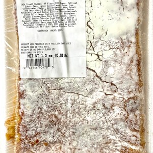 Peut inclure: Un gros plan sur un paquet de barres au citron. L'emballage est blanc avec du texte noir qui indique "Thank You For Your Patronage Lemon Bars". Les ingr&eacute;dients et les informations nutritionnelles sont indiqu&eacute;s sur l'emballage. Les barres au citron sont visibles &agrave; travers l'emballage en plastique.