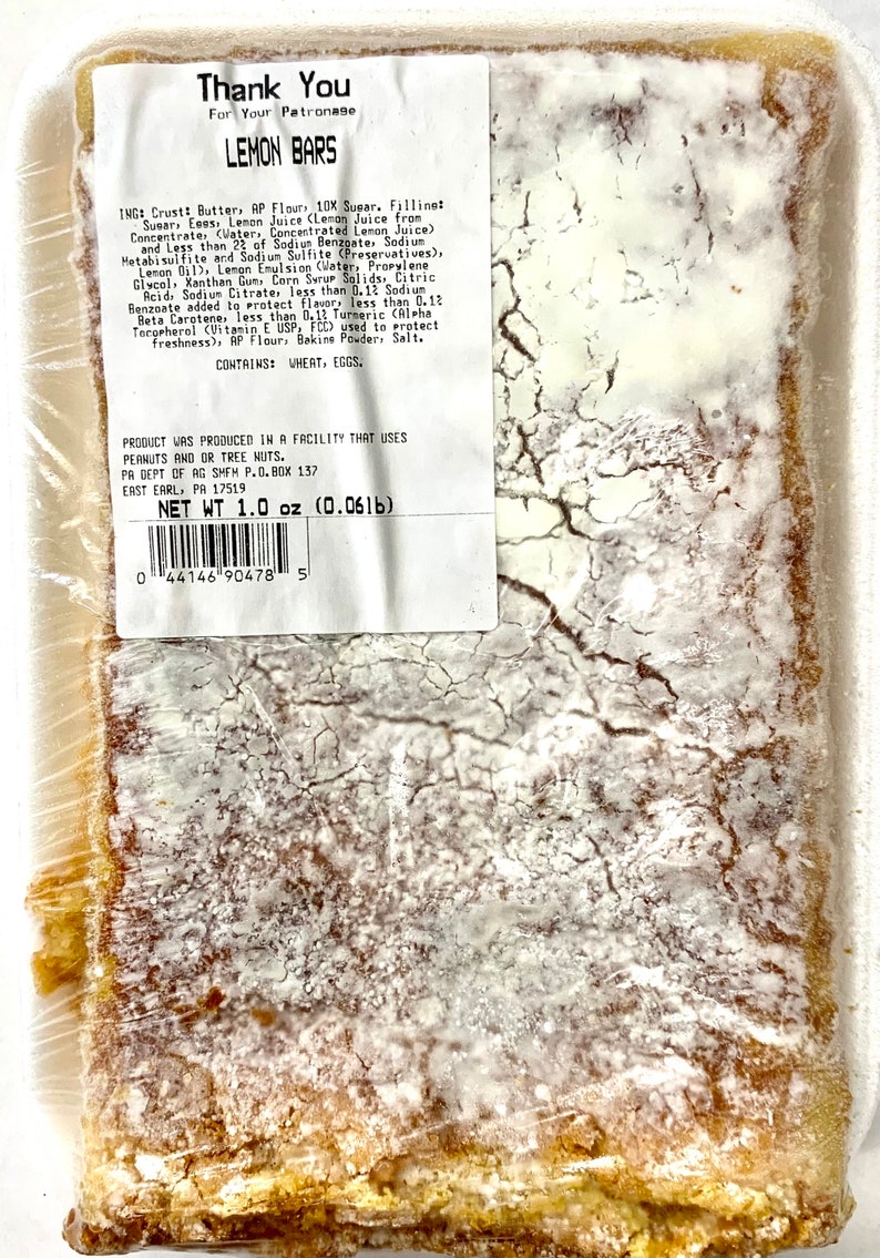 Peut inclure: Un gros plan sur un paquet de barres au citron. L'emballage est blanc avec du texte noir qui indique "Thank You For Your Patronage Lemon Bars". Les ingr&eacute;dients et les informations nutritionnelles sont indiqu&eacute;s sur l'emballage. Les barres au citron sont visibles &agrave; travers l'emballage en plastique.