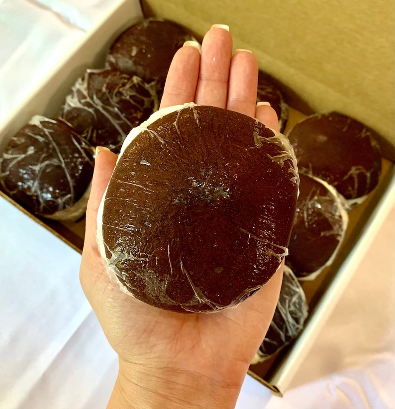 May include: A box of brown, round, individually wrapped fruits. The fruit is held in a hand for scale.