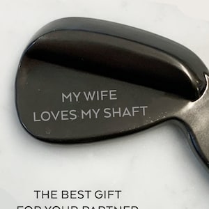 May include: A black golf club head with the text "MY WIFE LOVES MY SHAFT" engraved on it. The best gift for your partner.