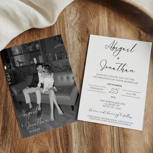May include: Two wedding invitations on a wooden tray. One features a black and white photo of a couple. The other has the names "Abigail + Jonathan" and wedding details, including the date.