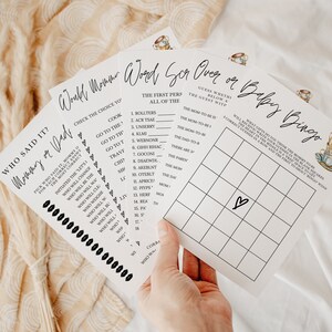 May include: A set of printable baby shower games with a black and white design. The games include "Who Said It? Mommy or Dad", "Word Scramble", "Over or Under", and "Baby Bingo".