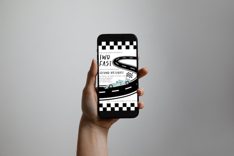 May include: A smartphone displaying a birthday invitation for a two-year-old. The invitation features a black and white checkered flag, a blue race car, and the text "Two Fast Second Birthday".
