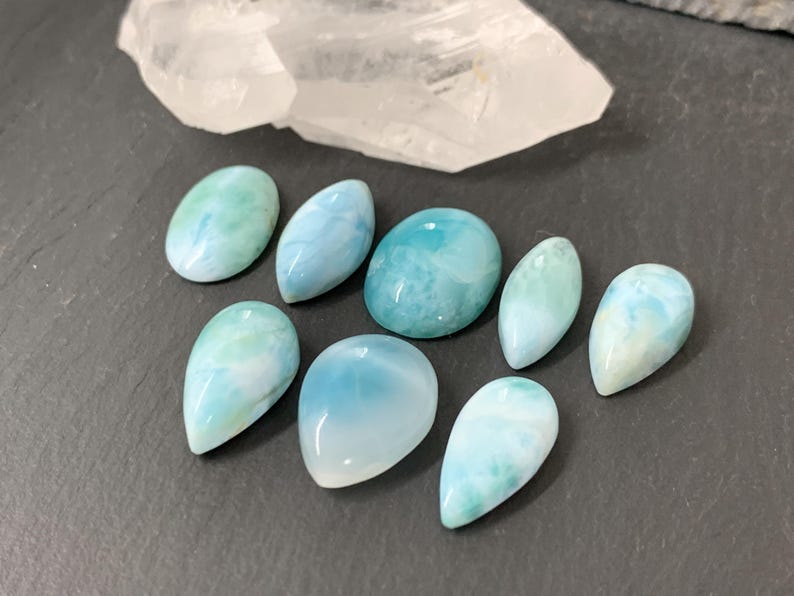 Peut inclure: Une collection de huit cabochons de pierres pr&eacute;cieuses en forme de larme, bleus et blancs. Les cabochons sont lisses et polis, avec une vari&eacute;t&eacute; de motifs tourbillonnants.