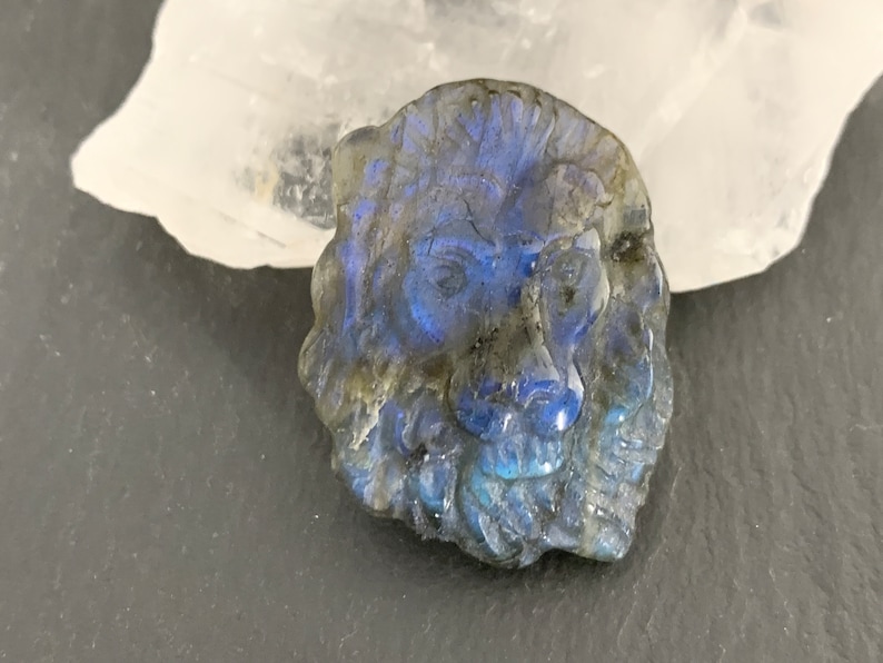 May include: A carved labradorite lion head pendant with iridescent blue and green colors.
