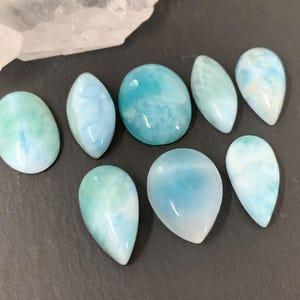 Peut inclure: Une collection de dix pierres pr&eacute;cieuses cabochon bleu clair et blanc avec une finition nacr&eacute;e. Les pierres pr&eacute;cieuses sont de diff&eacute;rentes tailles et formes, y compris en forme de larme et ovale.